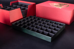 Duży zestaw zawierający kilka płaskich pudełek z kratownicami i zbiorcze, duże, czerwone pudełko z mocnymi wycięciami z boku. 