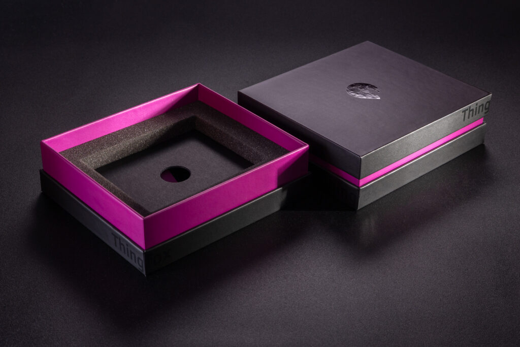 Luksusowe pudełko z fioletową burtą i czarnym spodem i wiekiem. Logo wydrukowane wybiórczym lakierem UV. Wypełnienie wykonane z pianki i kartonu.