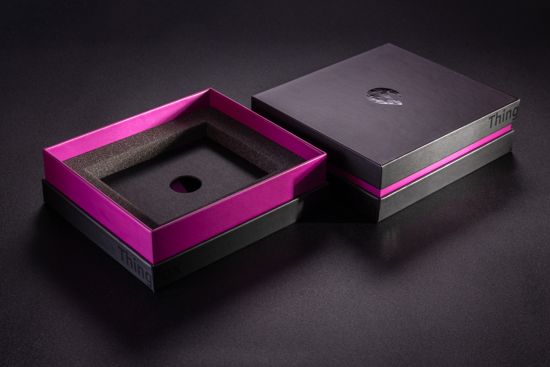 Luksusowe pudełko z fioletową burtą i czarnym spodem i wiekiem. Logo wydrukowane wybiórczym lakierem UV. Wypełnienie wykonane z pianki i kartonu. 