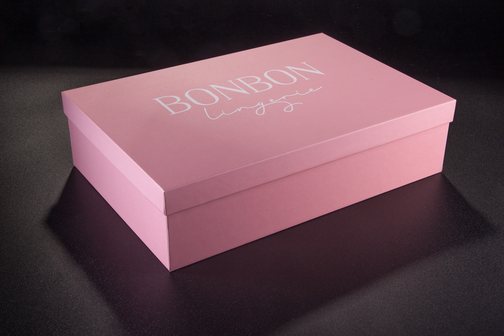 Różowe, rowkowane pudełko premium spód-wieczko z wydrukowanym logo na wierzchu. 