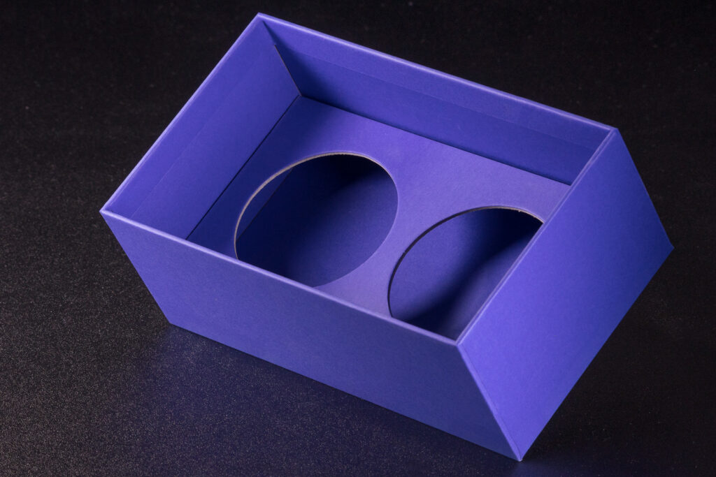 Wkładka, wypełnienie niebieskiego pudełka rigidbox wykonana z grubej, kaszerowanej tektury. Okrągłe sztancowane wycięcia na dwa słoiki.