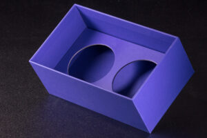 Wkładka, wypełnienie niebieskiego pudełka rigidbox wykonana z grubej, kaszerowanej tektury. Okrągłe sztancowane wycięcia na dwa słoiki. 