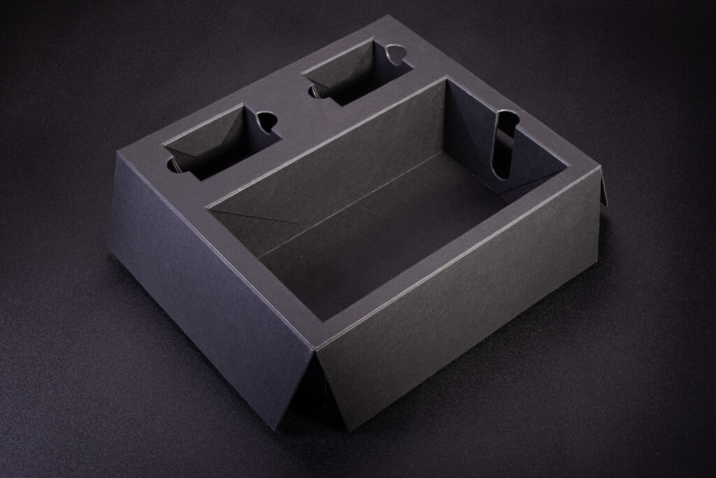 Wkładka z grubej czarnej w masie tektury i otworami zabezpieczonymi koszyczkami. Koszyczki powodują że otwory mają pełne boki.