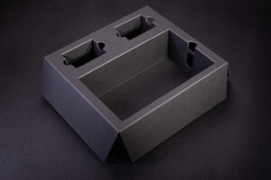 Wkładka z grubej czarnej w masie tektury i otworami zabezpieczonymi koszyczkami. Koszyczki powodują że otwory mają pełne boki.