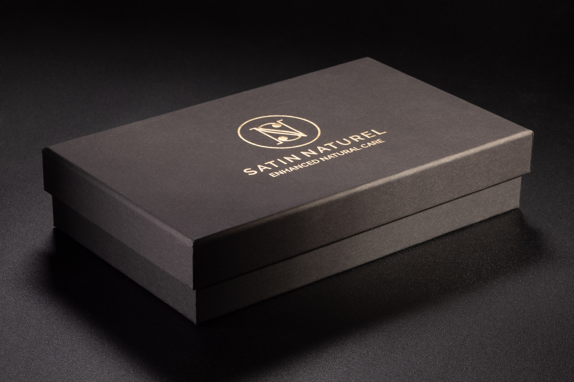 Czarne eleganckie pudełko spód wieko z wypukłym logiem w kolorze złotym na wieczku.