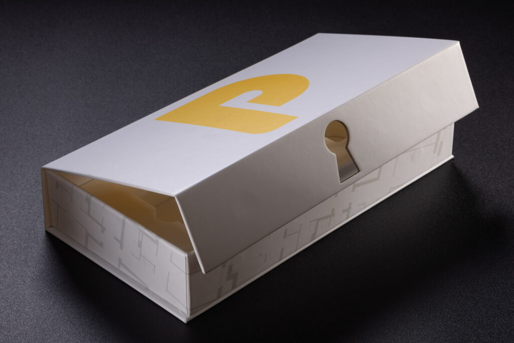 Sztancowany otwór w kształcie dziurki od klucza w klapce pudełka magnetycznego. 