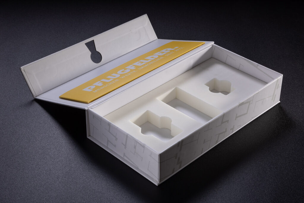 Wkładka z białej, gęstej pianki EVA z trzema otworami na produkty w pudełku z magnesami.