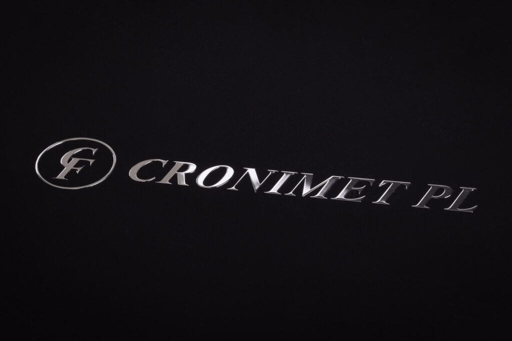 Logotym wykonany w metalu i naklejony na czarny papier